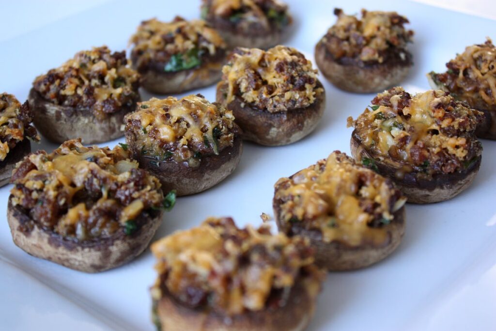 A plate of stuffed mushrooms with golden brown stuffing and herbs